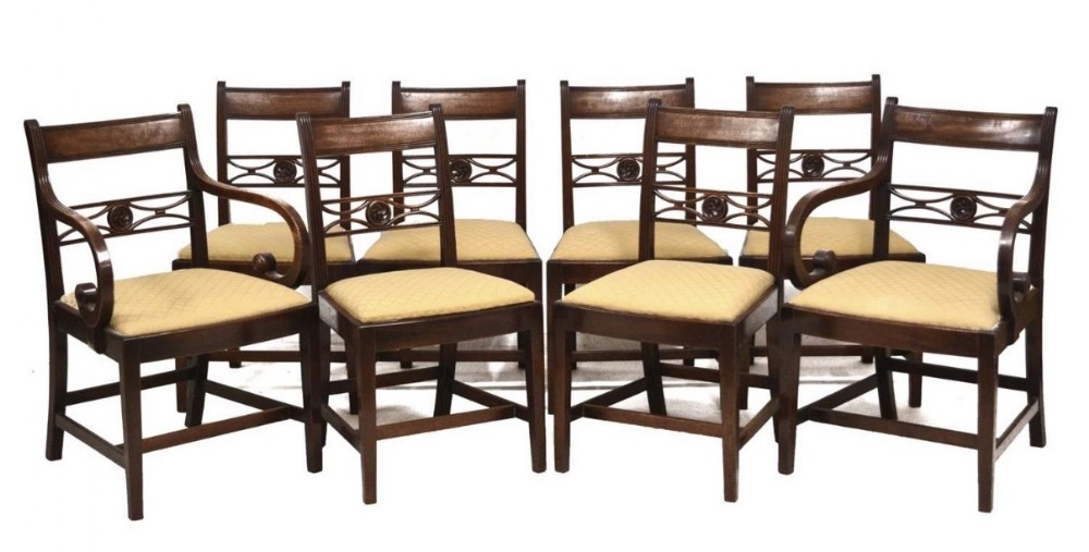 A set of eight late eighteenth-century George III mahogany dining chairs, comprising six side chairs and two armchairs with carved back rails and patterned yellow upholstered seats.