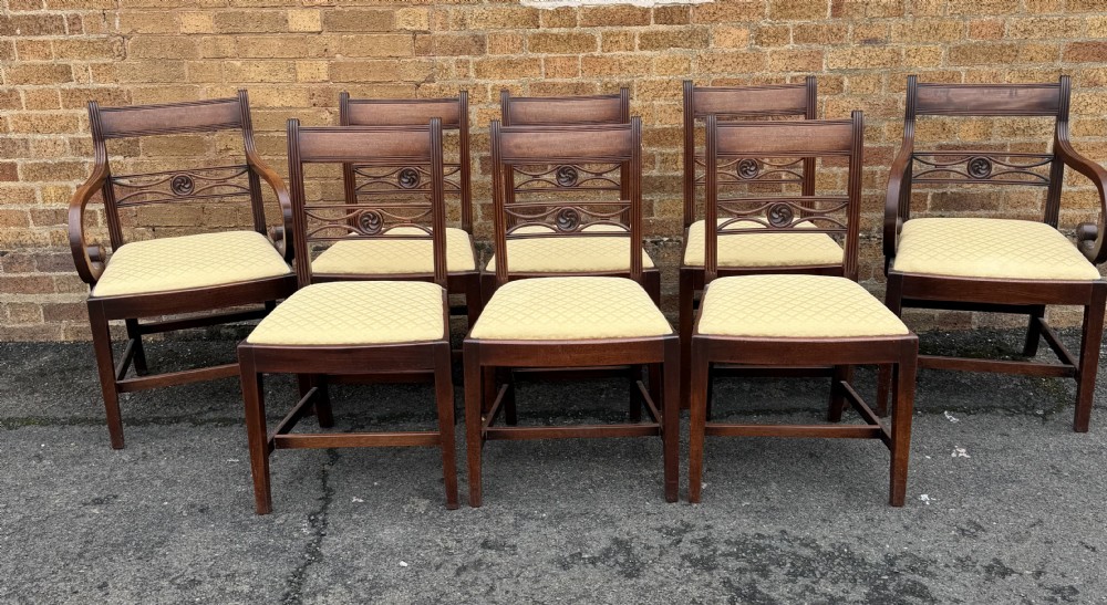 A set of eight late eighteenth-century George III mahogany dining chairs, comprising six side chairs and two armchairs with carved back rails and patterned yellow upholstered seats. View III
