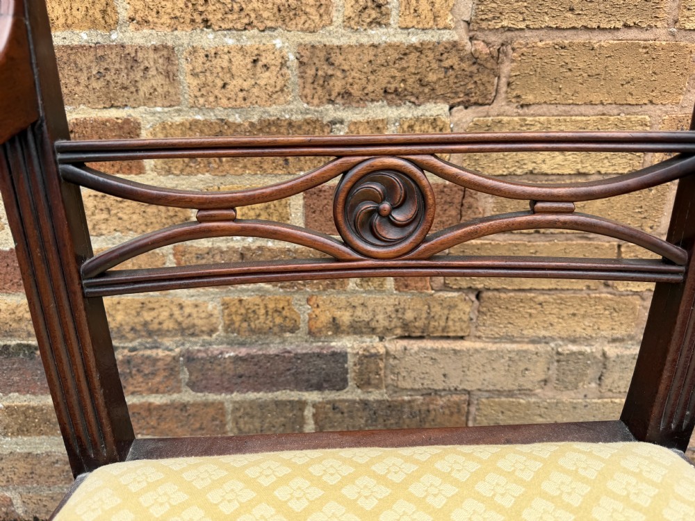 A set of eight late eighteenth-century George III mahogany dining chairs, comprising six side chairs and two armchairs with carved back rails and patterned yellow upholstered seats. View VII