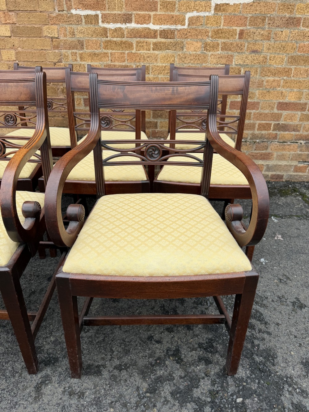 A set of eight late eighteenth-century George III mahogany dining chairs, comprising six side chairs and two armchairs with carved back rails and patterned yellow upholstered seats. View XIII