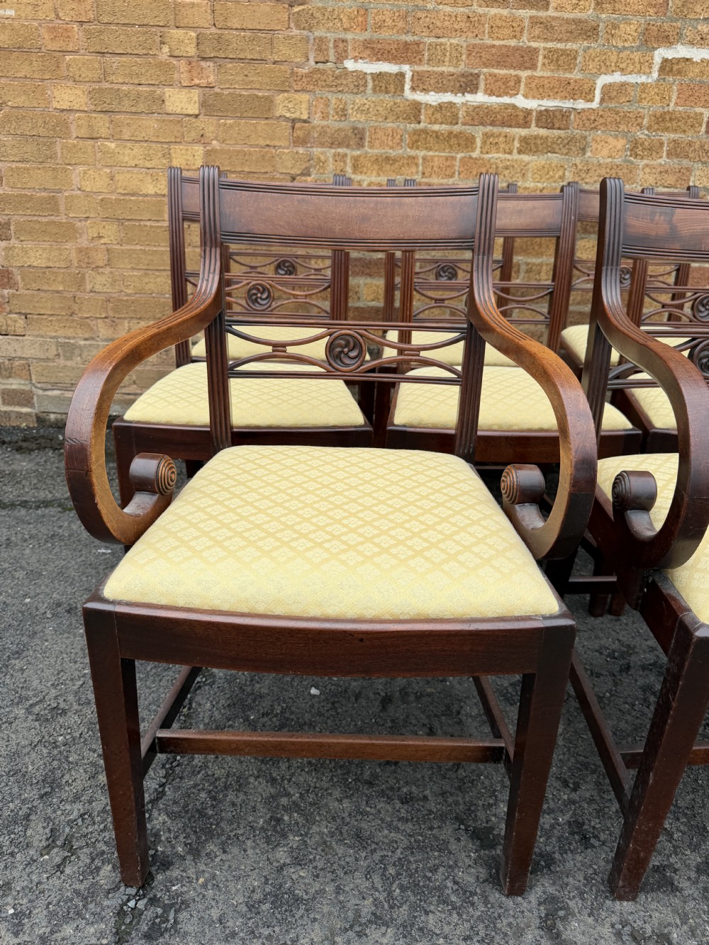 A set of eight late eighteenth-century George III mahogany dining chairs, comprising six side chairs and two armchairs with carved back rails and patterned yellow upholstered seats. View XIV