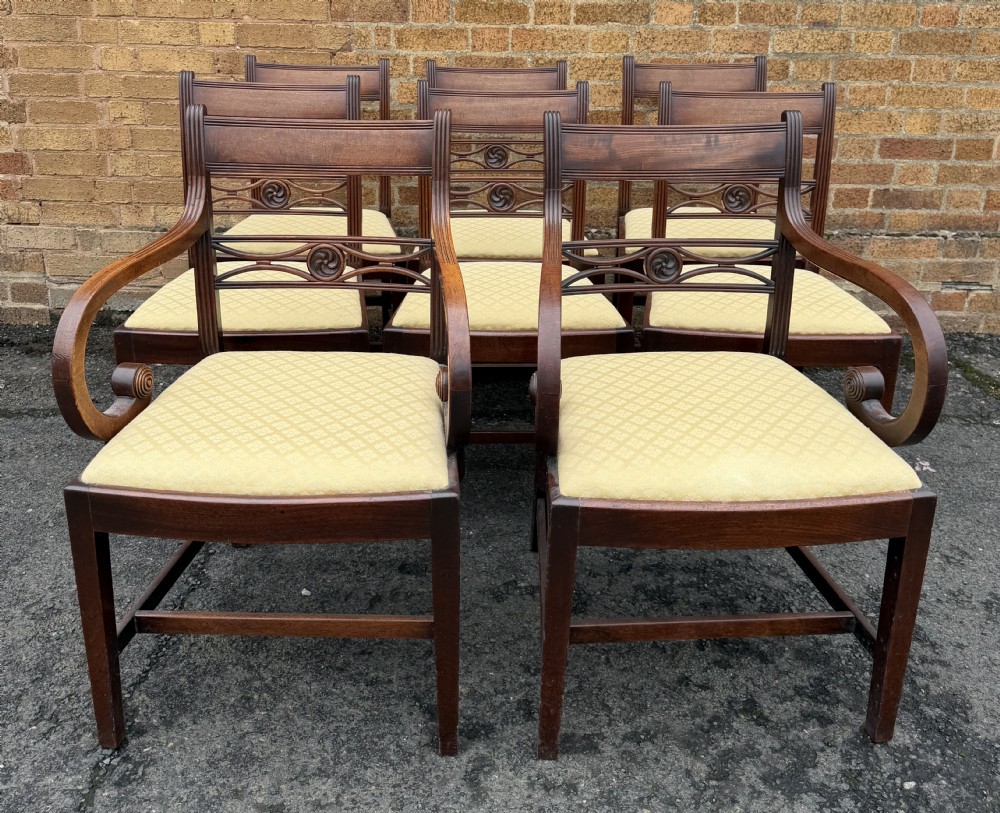 A set of eight late eighteenth-century George III mahogany dining chairs, comprising six side chairs and two armchairs with carved back rails and patterned yellow upholstered seats. View XVIII