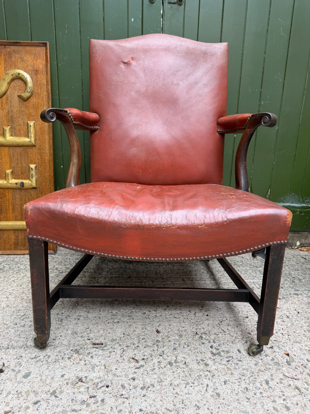 An 18th-century George III Gainsborough library armchair upholstered in aged red leather with a mahogany frame, padded armrests, brass stud trim, and brass castors. View II