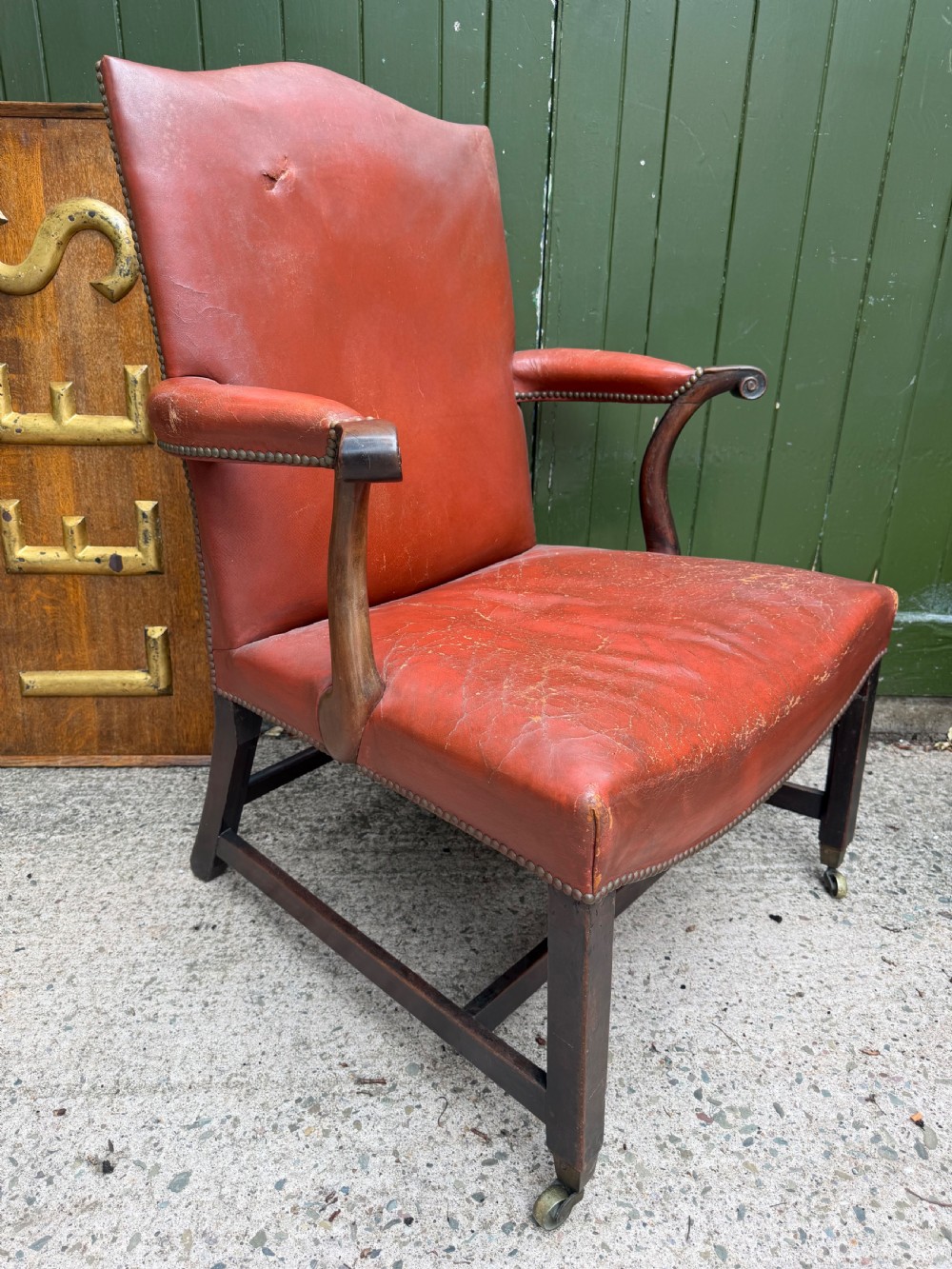 An 18th-century George III Gainsborough library armchair upholstered in aged red leather with a mahogany frame, padded armrests, brass stud trim, and brass castors. View III