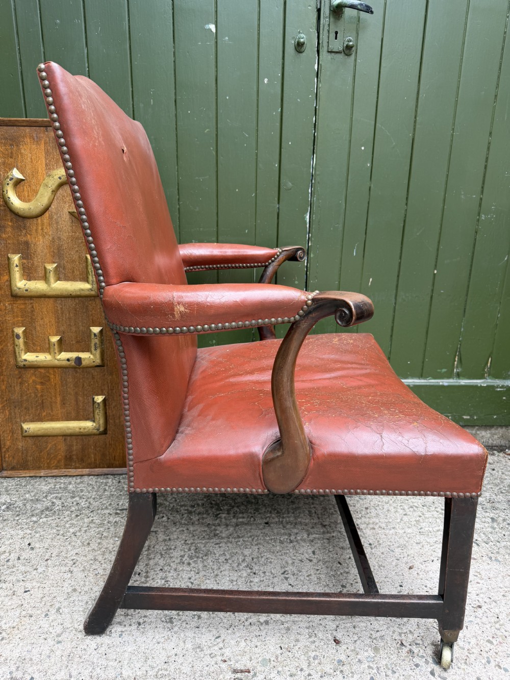 An 18th-century George III Gainsborough library armchair upholstered in aged red leather with a mahogany frame, padded armrests, brass stud trim, and brass castors. View V