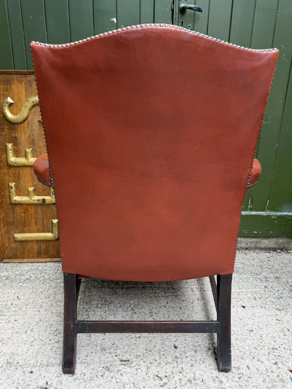 An 18th-century George III Gainsborough library armchair upholstered in aged red leather with a mahogany frame, padded armrests, brass stud trim, and brass castors. View VI