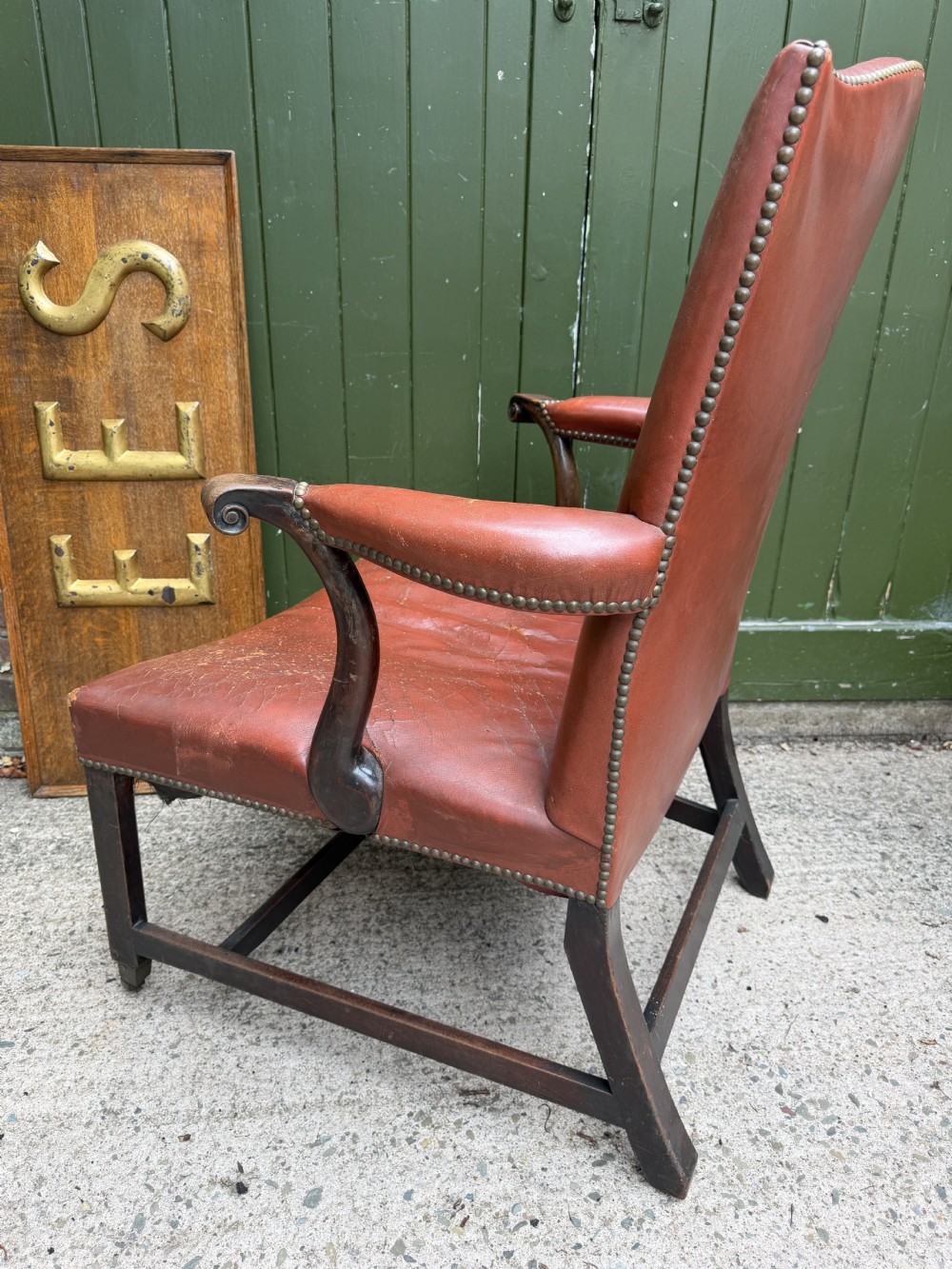An 18th-century George III Gainsborough library armchair upholstered in aged red leather with a mahogany frame, padded armrests, brass stud trim, and brass castors. View VII