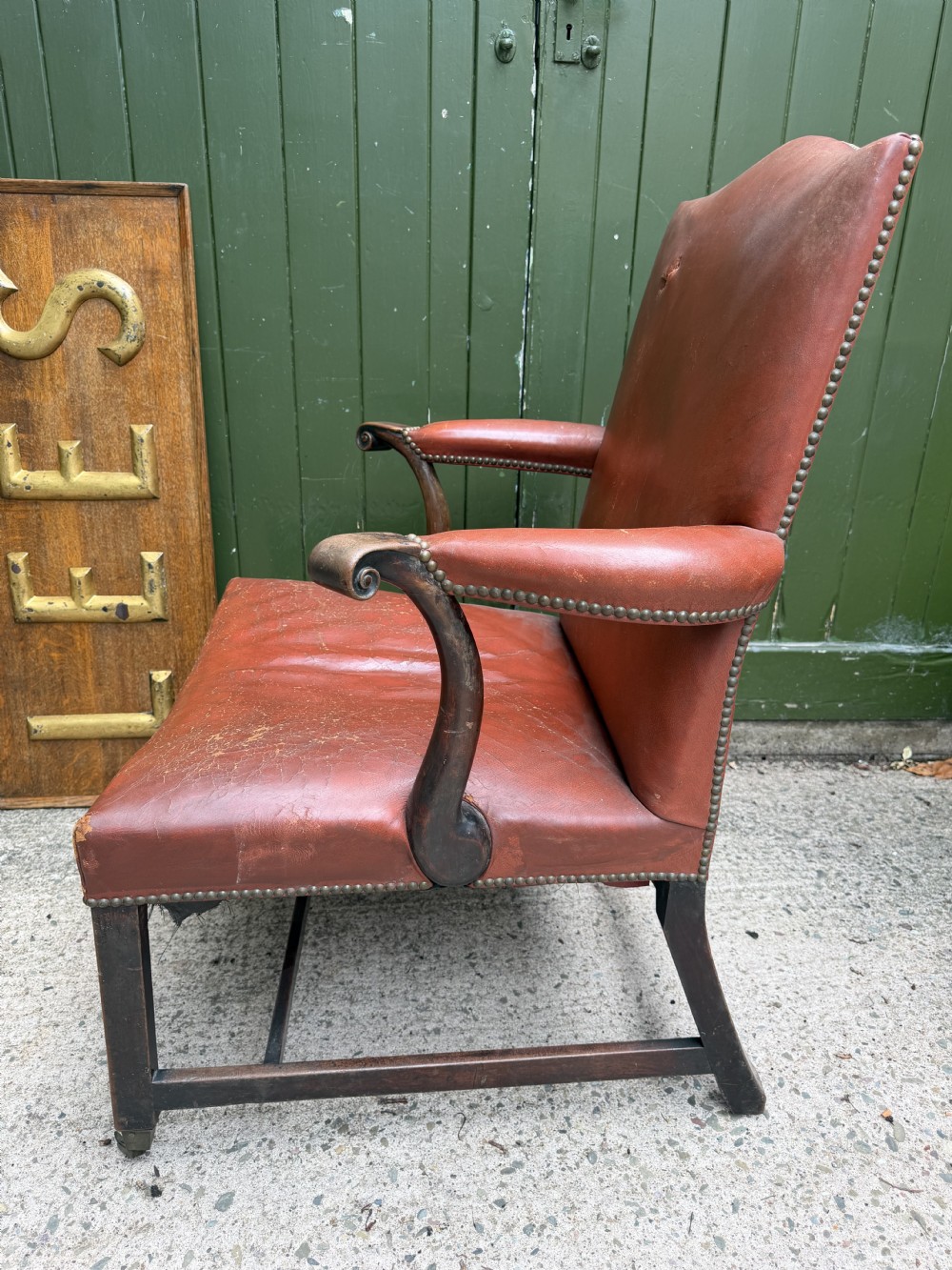 An 18th-century George III Gainsborough library armchair upholstered in aged red leather with a mahogany frame, padded armrests, brass stud trim, and brass castors. View VIII