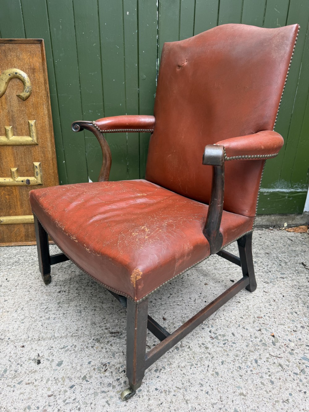 An 18th-century George III Gainsborough library armchair upholstered in aged red leather with a mahogany frame, padded armrests, brass stud trim, and brass castors. View XI