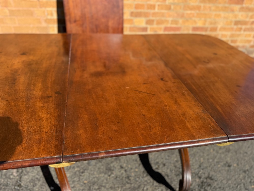 An early 19th-century George III twin-pillar mahogany dining table featuring reeded splayed legs and original brass castors. View IV