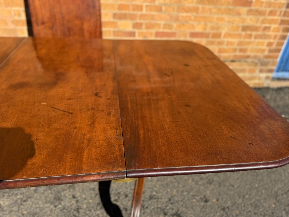 An early 19th-century George III twin-pillar mahogany dining table featuring reeded splayed legs and original brass castors. View V
