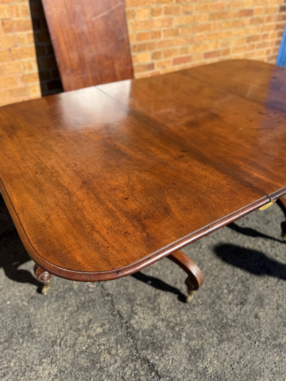 An early 19th-century George III twin-pillar mahogany dining table featuring reeded splayed legs and original brass castors. View VI