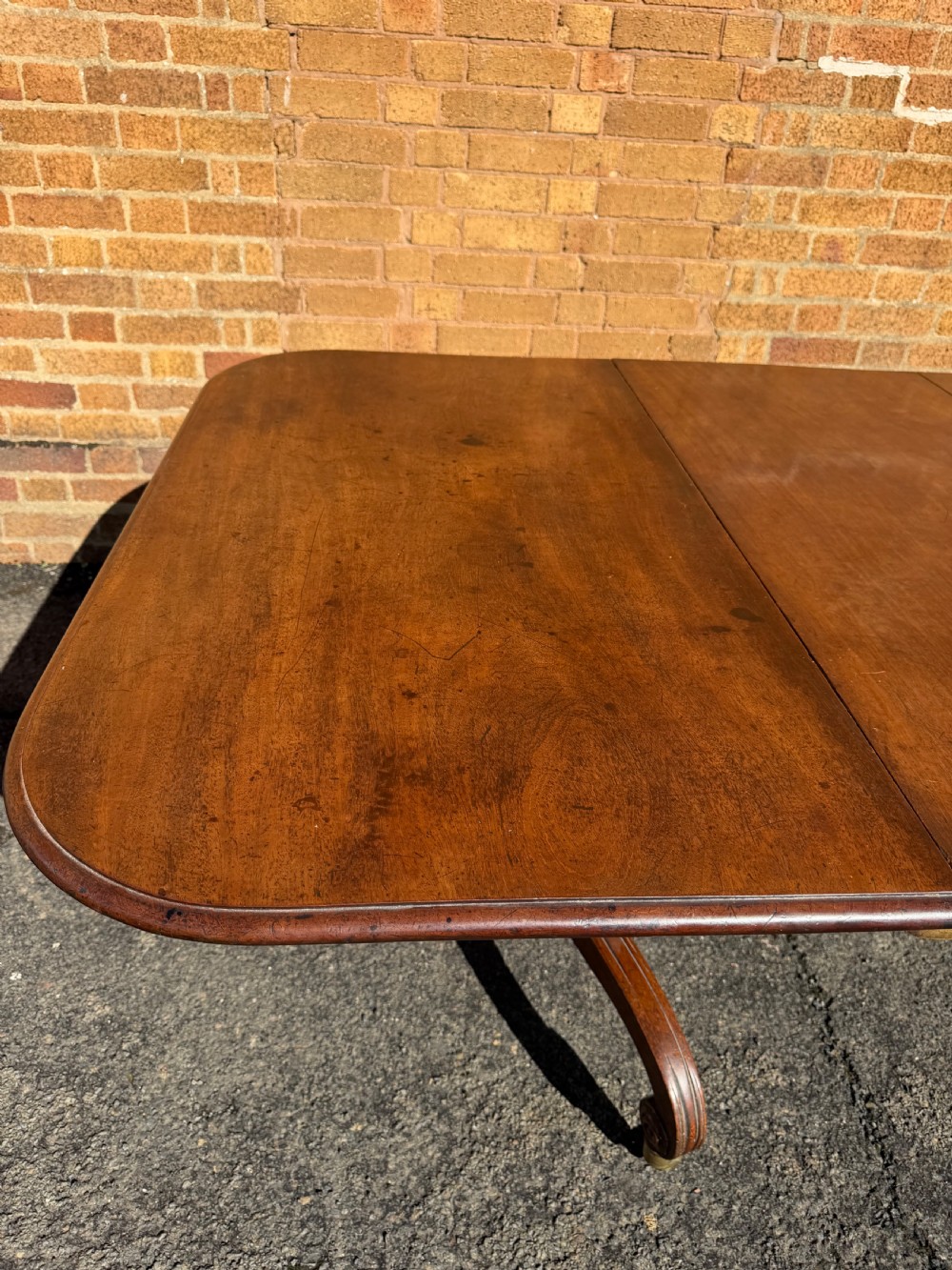 An early 19th-century George III twin-pillar mahogany dining table featuring reeded splayed legs and original brass castors. View VIII
