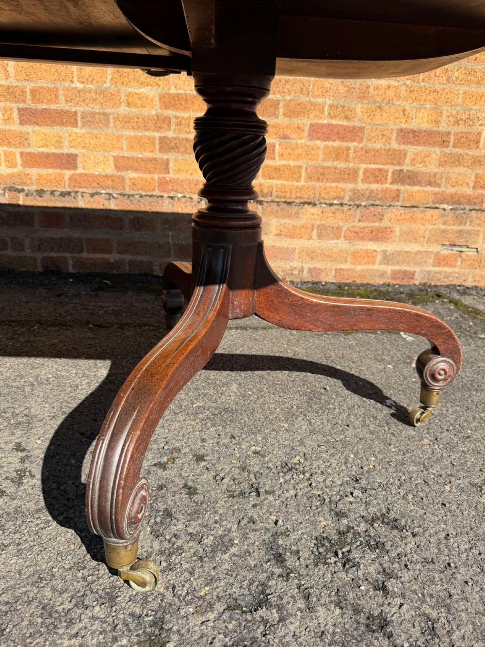 An early 19th-century George III twin-pillar mahogany dining table featuring reeded splayed legs and original brass castors. View IX