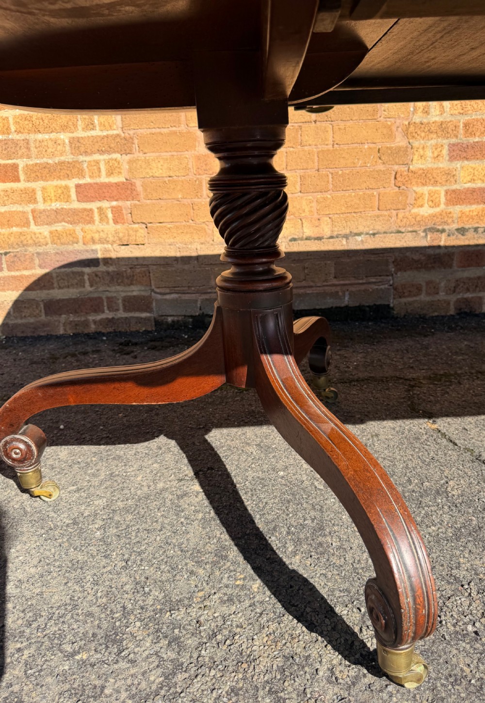 An early 19th-century George III twin-pillar mahogany dining table featuring reeded splayed legs and original brass castors. View X