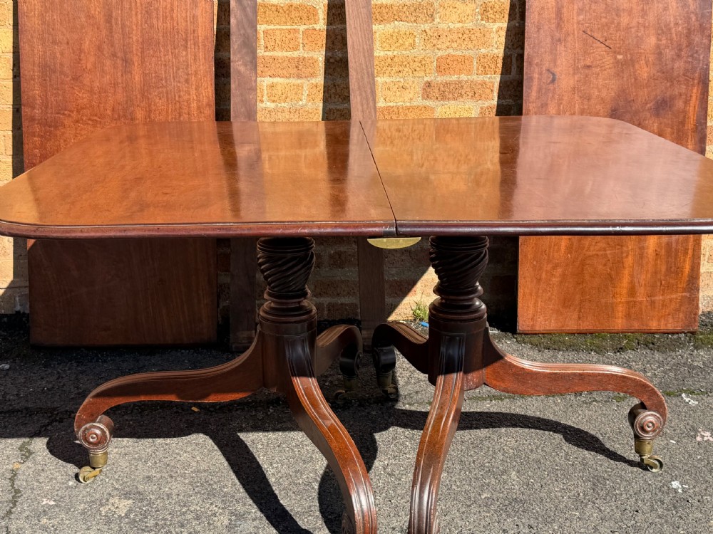 An early 19th-century George III twin-pillar mahogany dining table featuring reeded splayed legs and original brass castors. View XIII