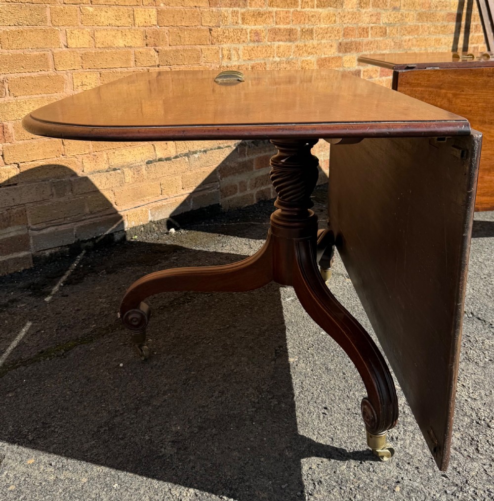 An early 19th-century George III twin-pillar mahogany dining table featuring reeded splayed legs and original brass castors. View XV