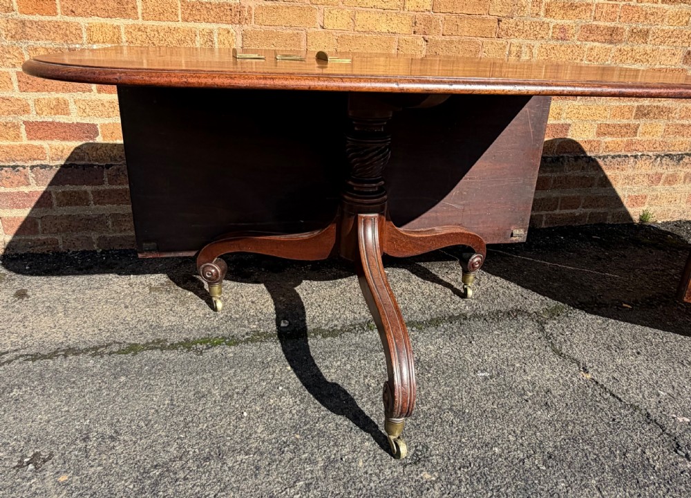 An early 19th-century George III twin-pillar mahogany dining table featuring reeded splayed legs and original brass castors. View XVI