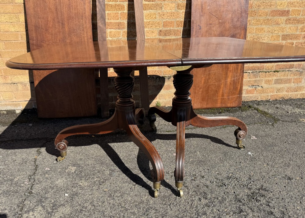 An early 19th-century George III twin-pillar mahogany dining table featuring reeded splayed legs and original brass castors. View XXI