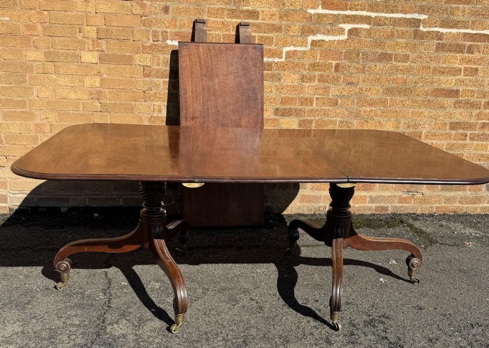An early 19th-century George III twin-pillar mahogany dining table featuring reeded splayed legs and original brass castors. View XXII