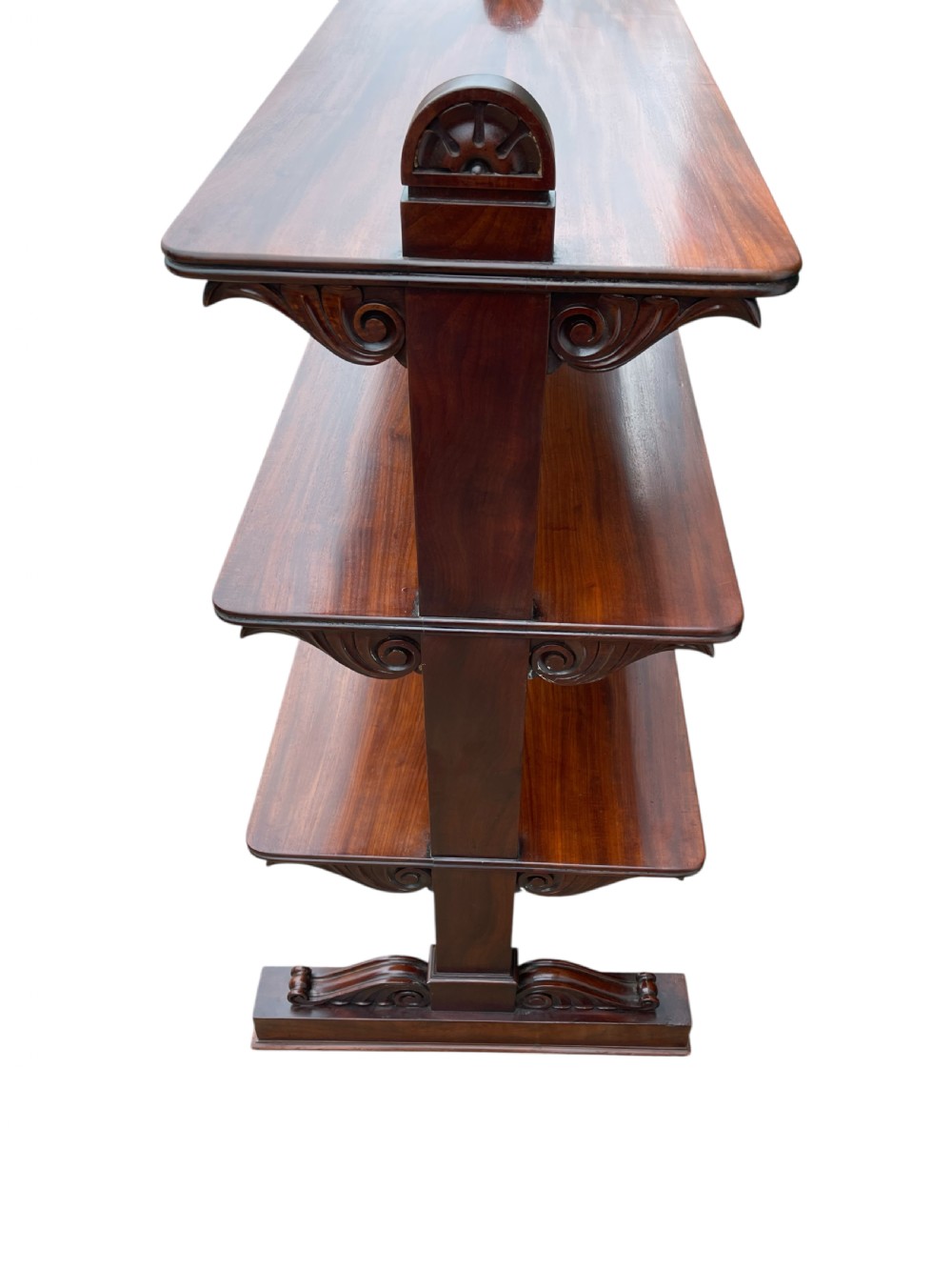 A nineteenth-century mahogany three-tiered dumb waiter featuring carved side uprights and fitted with brass castors at the base. View IV
