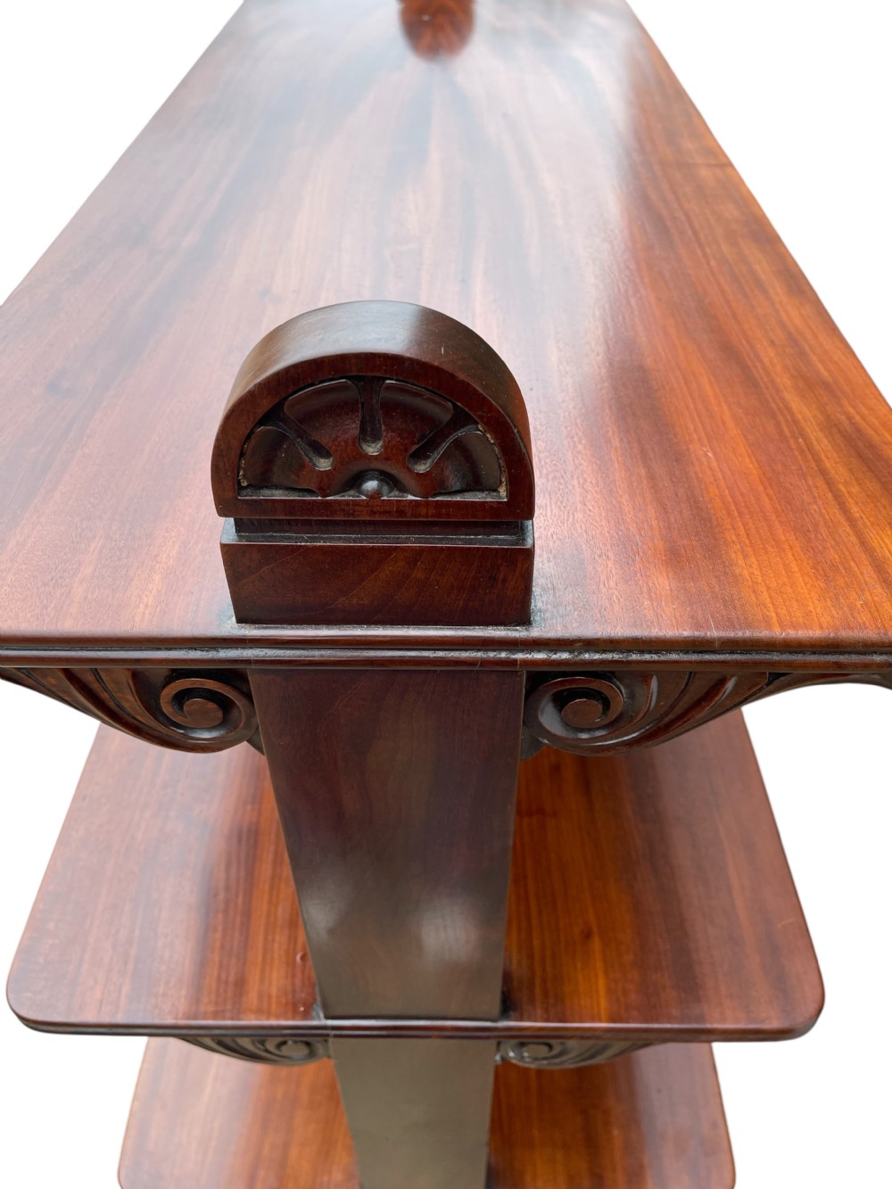 A nineteenth-century mahogany three-tiered dumb waiter featuring carved side uprights and fitted with brass castors at the base. View III