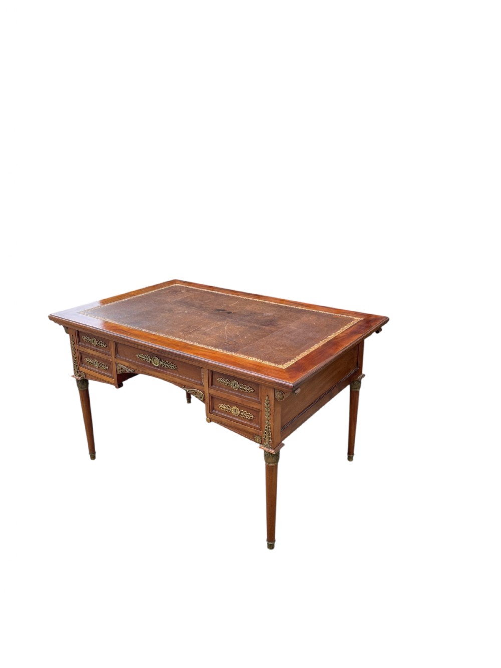 A French Empire style mahogany writing desk featuring a gilt-tooled leather writing surface, pull-out side slides, ormolu brass mounts, and tapered legs. View II