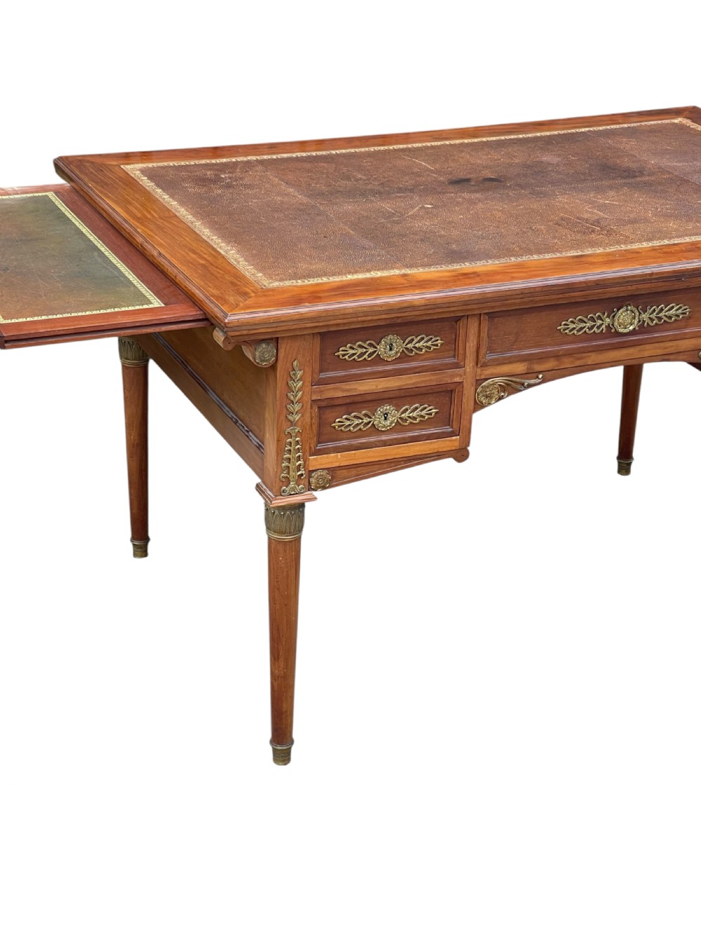 A French Empire style mahogany writing desk featuring a gilt-tooled leather writing surface, pull-out side slides, ormolu brass mounts, and tapered legs. View III