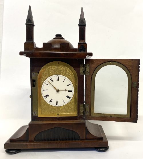 fig 1. A miniature architectural mahogany mantel clock with corner spires, a domed roof, and an engraved brass dial with Roman numerals.