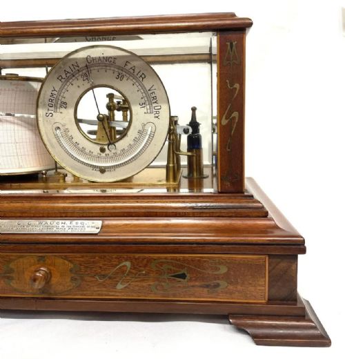 fig 2. An Art Nouveau mahogany barograph featuring a glazed display case, stylized inlay on the timber frame and base drawer, an internal recording drum, and a silvered barometer dial.