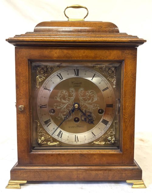 fig 1. A burr walnut basket top mantel clock featuring an etched brass dial with Roman numerals, corner spandrels, side glass panels, and a top brass handle.