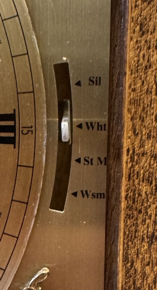 A burr walnut basket top mantel clock featuring an etched brass dial with Roman numerals, corner spandrels, side glass panels, and a top brass handle. View V