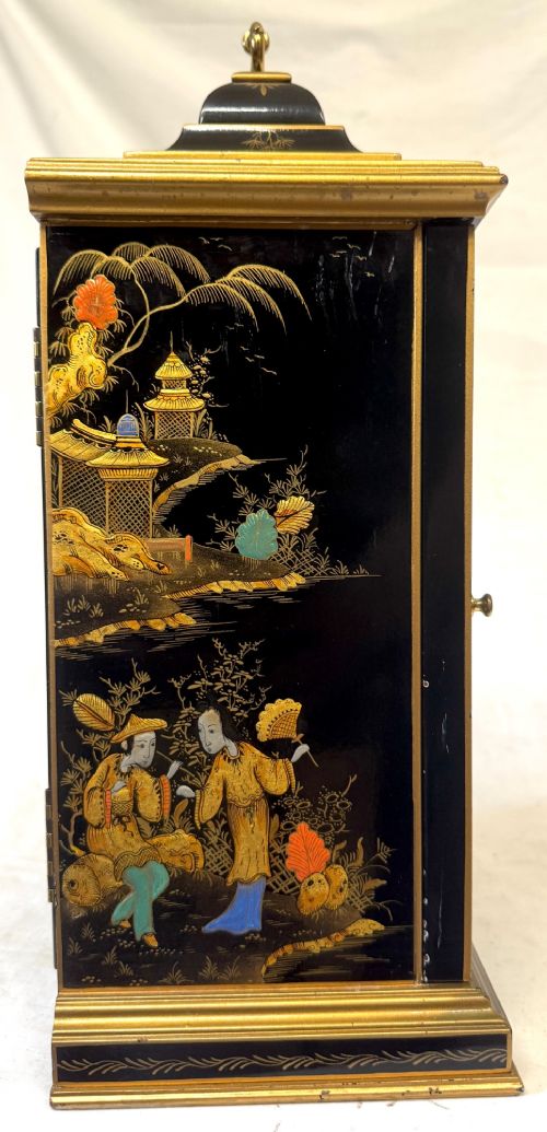 A black lacquered chinoiserie bracket clock featuring hand-painted gilt landscape scenes, a brass dial with Roman numerals, and a top brass carrying handle. View VII