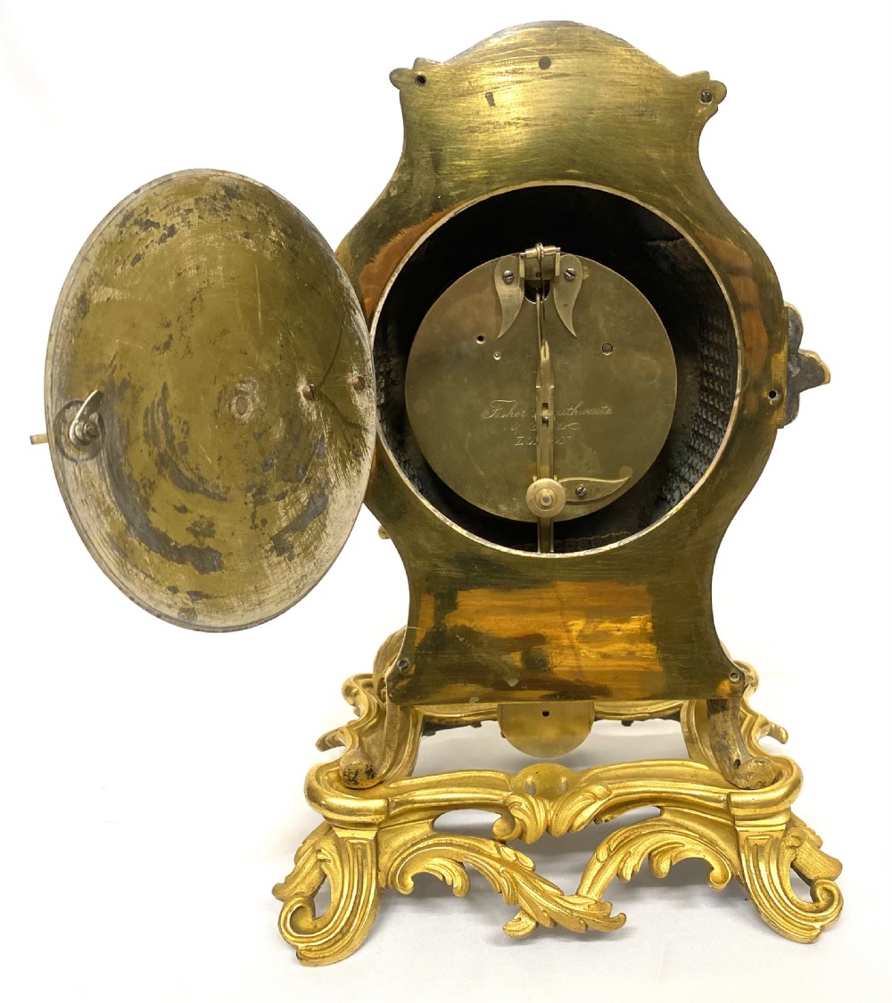 A Rococo style gilt bronze mantel clock featuring scrollwork, acanthus leaf carving, and a gilded dial with Roman numerals. View IX