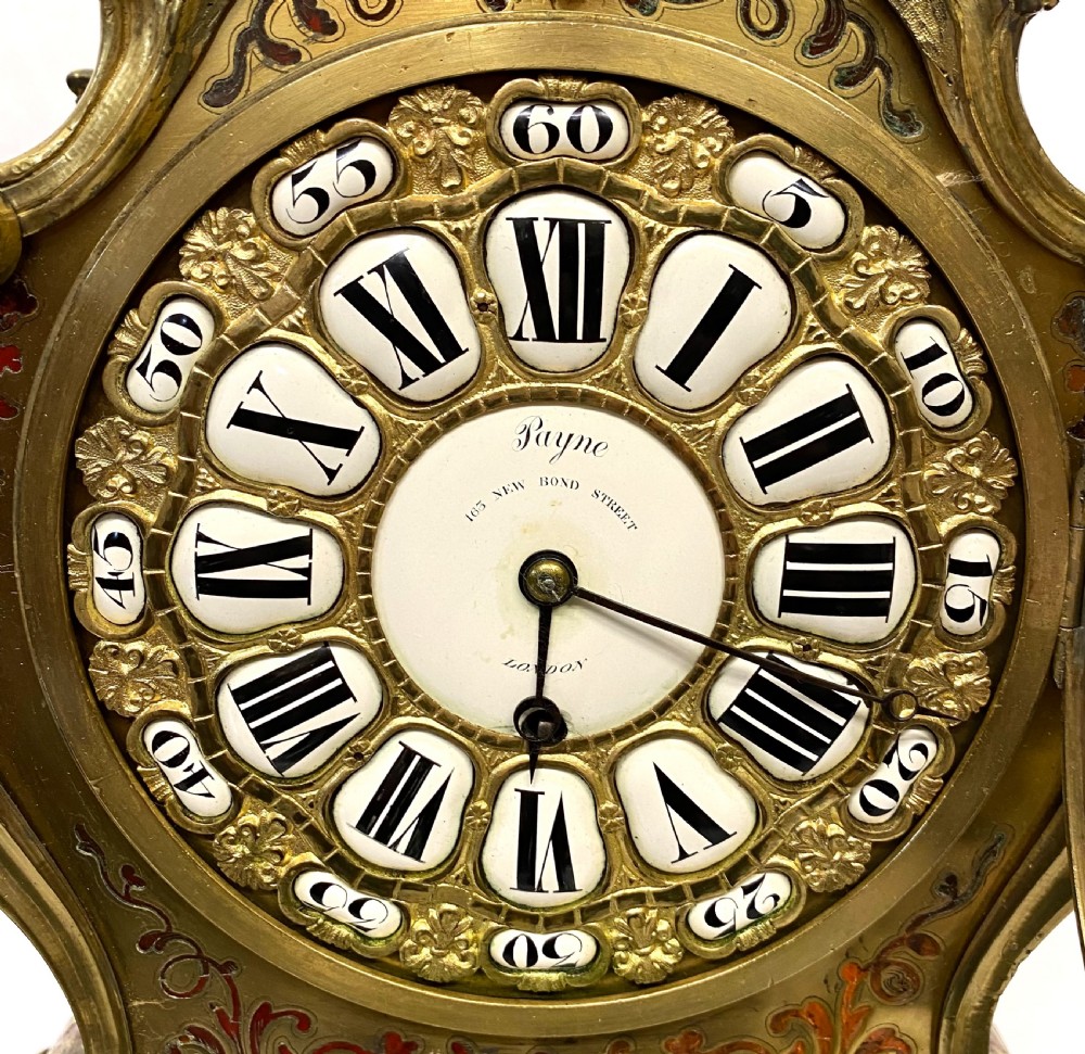 An ornate Rococo Revival mantel clock featuring brass and tortoiseshell Boulle marquetry inlay, gilt mounts, and individual white enamel cartouche Roman numerals on a matching plinth base. View III