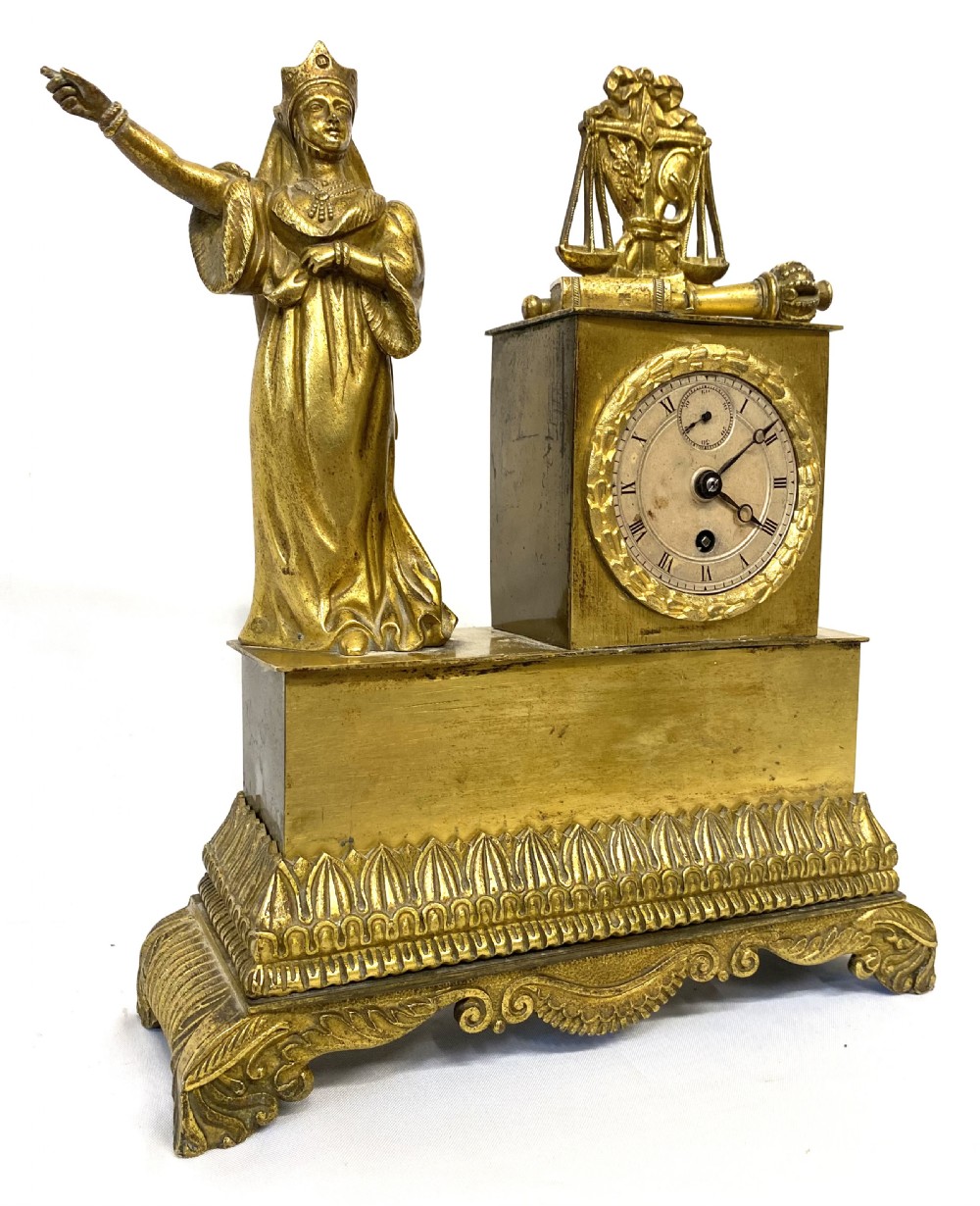A nineteenth-century French gilt bronze mantel clock featuring a standing female figure beside a square clock casing surmounted by scales of justice.