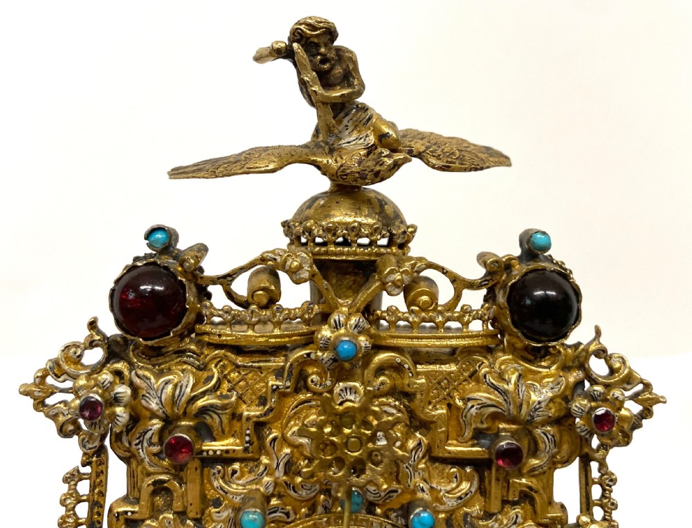 An ornate gilt-silver zappler clock featuring elaborate scrollwork, inset turquoise cabochons, dark garnet gemstones, and sculpted figurative finials on an elevated base. View III