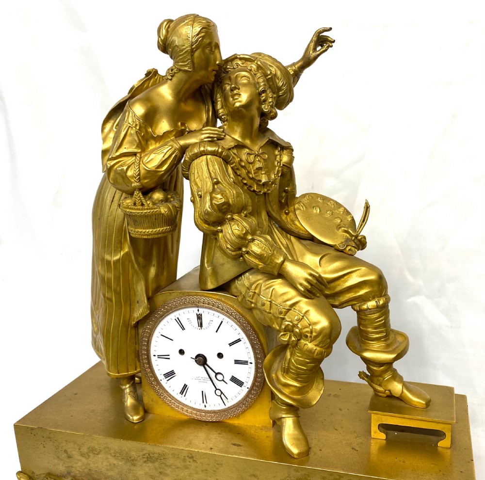A nineteenth-century gilt bronze figural mantel clock depicting a seated artist and companion figure above a white enamel dial with Roman numerals. View IV