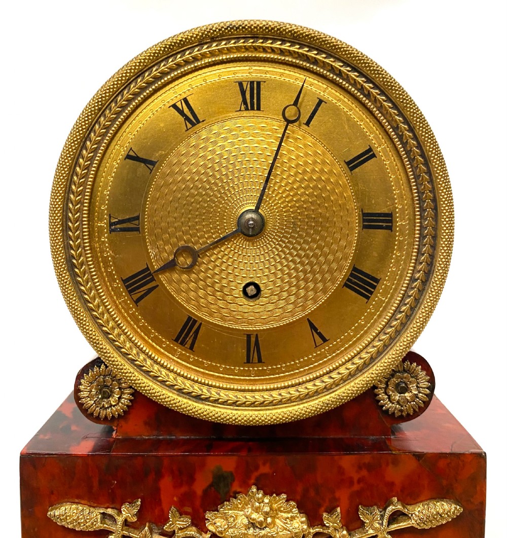 A Regency ormolu mantel clock with an engine-turned gold dial, floral gilt mounts, and a white marble plinth resting on brass feet. View III