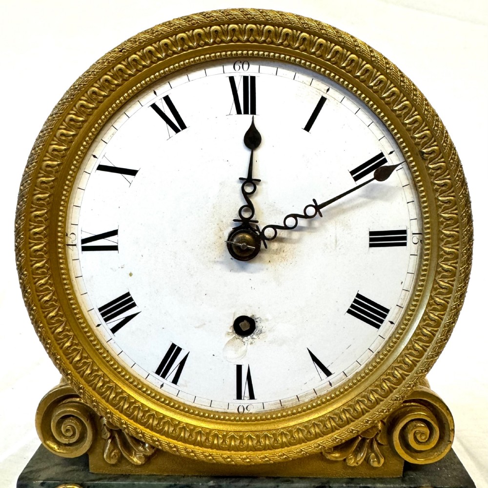 A Regency mantel clock featuring a white enamel dial with Roman numerals set above a green marble base adorned with gilt-bronze floral swags. View III