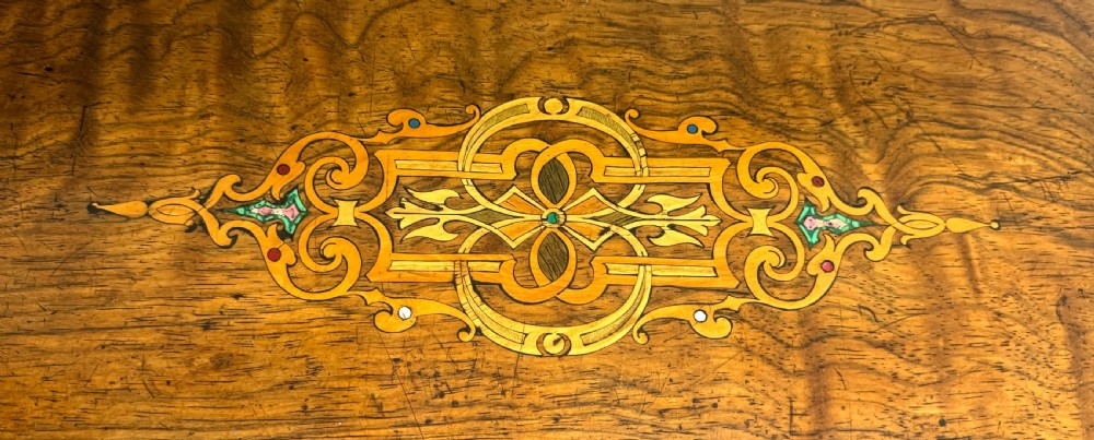 An antique rectangular wooden music box featuring floral marquetry inlay on the lid and front, framed by dark ebonised edges with a key inserted in the lock. View IV