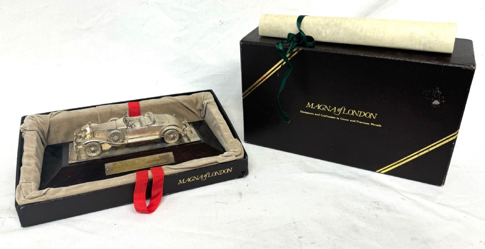 A solid silver model of a classic Rolls Royce Phantom II roadster mounted on a dark wooden plinth inside a presentation box.