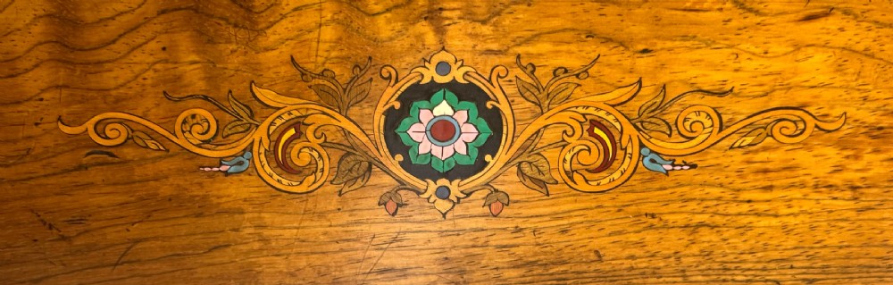 A rectangular rosewood music box featuring floral marquetry inlays on the lid and front panel, flanked by ebonised borders with a key inserted. View V