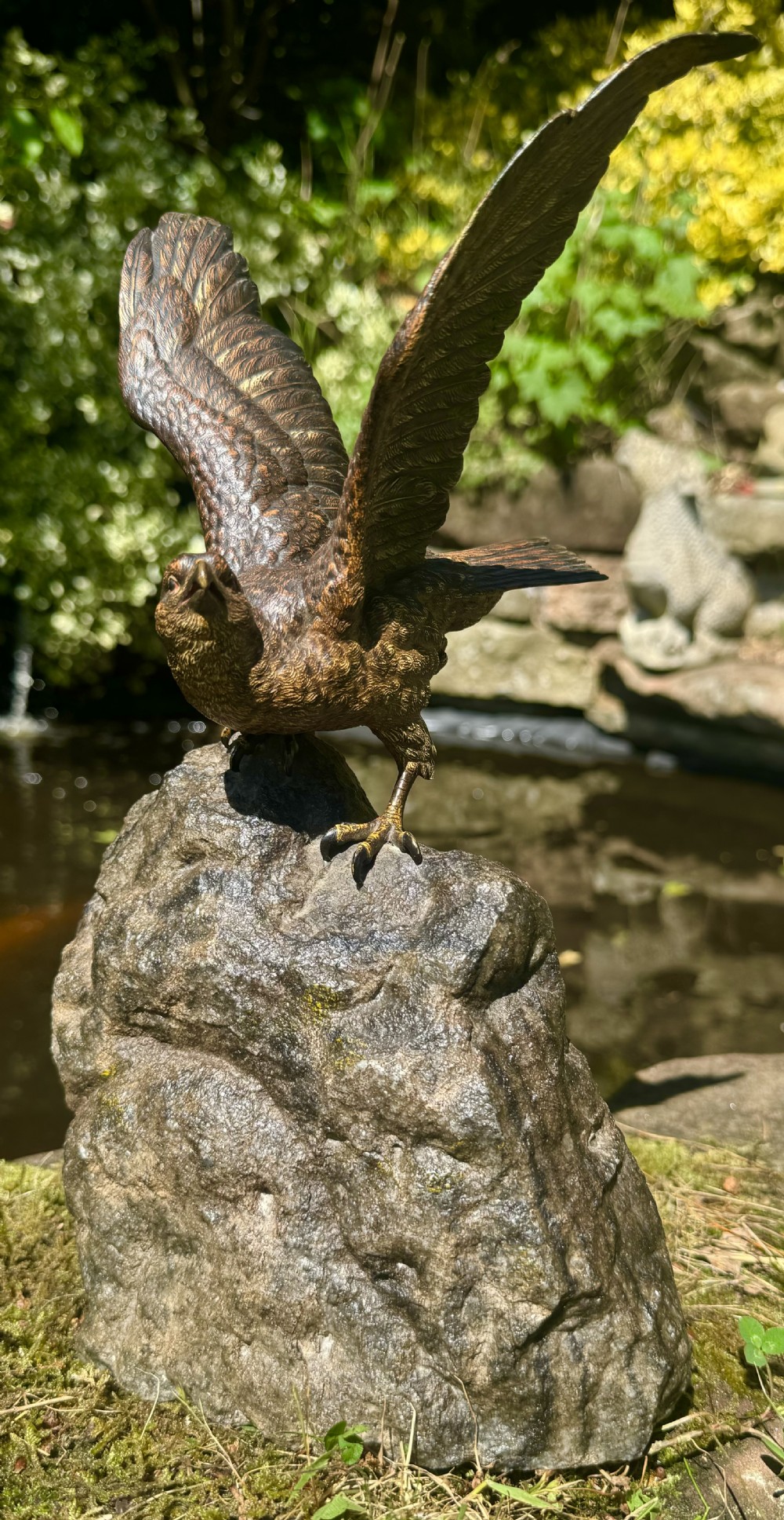 A cold-painted bronze sculpture depicting a hawk with open wings perched atop a natural quartz stone base. View II