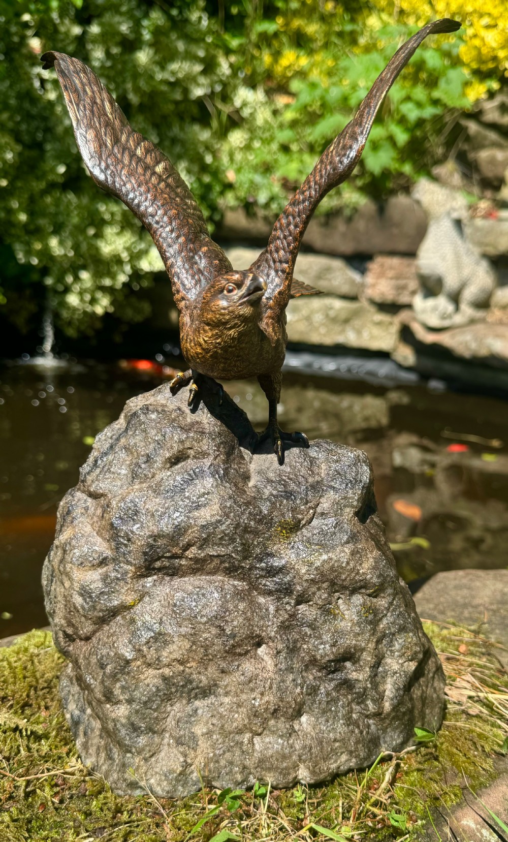 A cold-painted bronze sculpture depicting a hawk with open wings perched atop a natural quartz stone base. View III