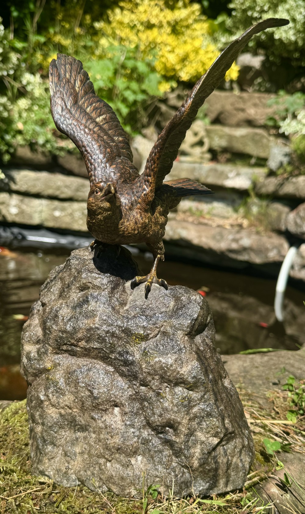 A cold-painted bronze sculpture depicting a hawk with open wings perched atop a natural quartz stone base. View IV