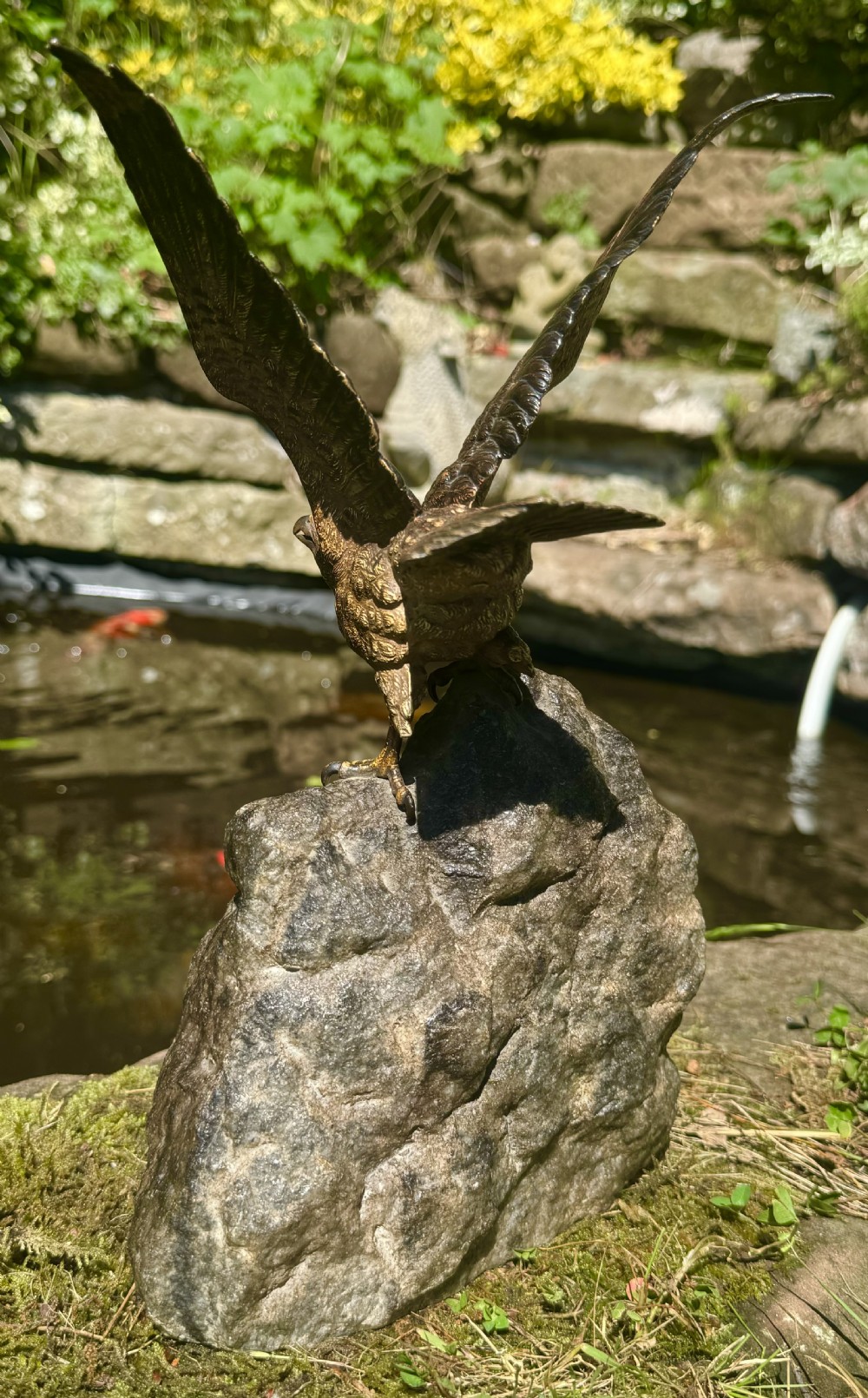 A cold-painted bronze sculpture depicting a hawk with open wings perched atop a natural quartz stone base. View XI