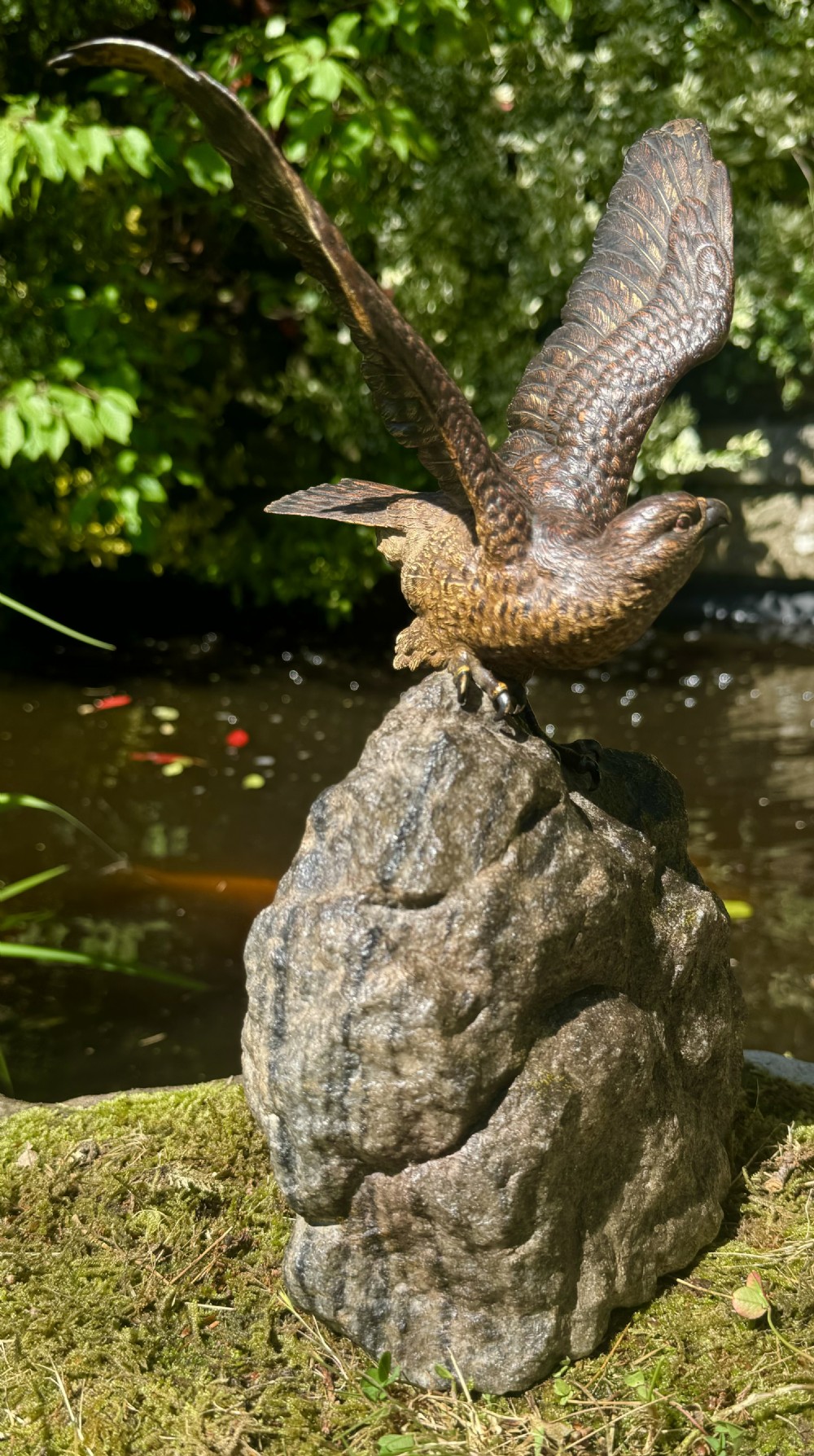 A cold-painted bronze sculpture depicting a hawk with open wings perched atop a natural quartz stone base. View XXI