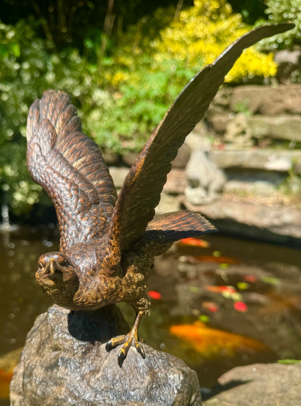 A cold-painted bronze sculpture depicting a hawk with open wings perched atop a natural quartz stone base. View XXIII