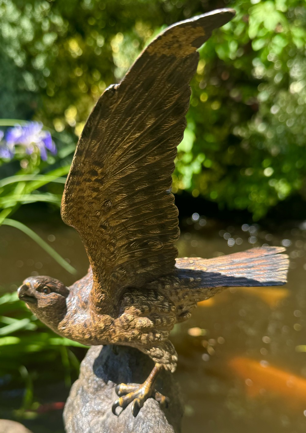 A cold-painted bronze sculpture depicting a hawk with open wings perched atop a natural quartz stone base. View XXV